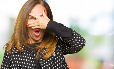 Yüz ve gözler el ile kapsayan şok ceket moda bakmak giyen güzel orta yaş kadın mahcup ifadeyle parmaklarımın arasından arıyorsunuz.