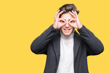 Zarif delikanlı üzerinde kış palto giyiyor, dilini parmaklarının arasından baktığını yapışmasını dürbün gibi ok jest yapıyor arka plan izole. Deli ifade.