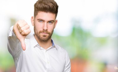 Mutsuz ve kızgın ret gösterilen ve başparmak aşağı hareketi ile negatif görünümlü genç yakışıklı iş adamı. Kötü ifade.