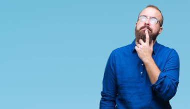 Çene düşünme hakkında soru, dalgın ifade üzerine el ile izole arka plan üzerinde gözlük takan Genç beyaz hipster adam. Düşünceli yüzüyle gülümsüyor. Şüphe kavramı.