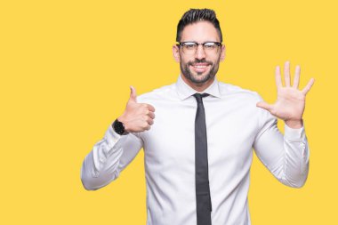 Gösterilen arka plan üzerinde gözlük takan genç yakışıklı iş adamı izole ve parmakları ile işaret kendinden emin ve mutlu gülümseyerek süre 6 numara.