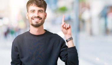 Yakışıklı delikanlı gösterilen ve kendinden emin ve mutlu gülümseyen bir parmak ile işaret eden oktan yukarı izole arka plan üzerinde.