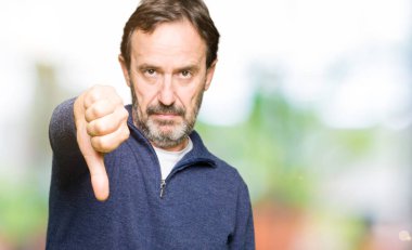 Orta yaş yakışıklı adam mutsuz ve kızgın ret gösterilen ve başparmak aşağı hareketi ile negatif seyir bir kazak giyiyor. Kötü ifade.