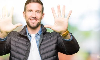 Kış ceket gösterme ve parmakları ile işaret giyen yakışıklı adam kendinden emin ve mutlu gülümseyerek süre on numara.