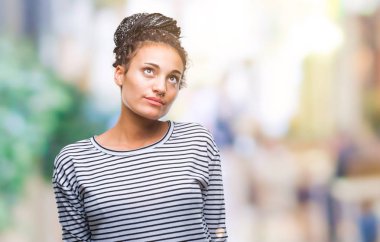 Genç görünümlü yan ve dik dik bakma uzağa düşünce gülümseyen izole arka plan üzerinde kazak giyen Afro-Amerikan kız saç örgülü.