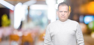 Orta yaş Arap adam sorunu nedeniyle izole arka plan şüpheci ve sinir, papatyanın üzgün üzerinde spor kazak giyiyor. Negatif kişi.