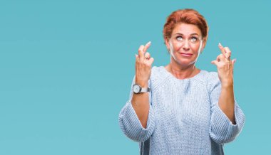 Umut ve gözleri kapalı geçiş parmaklarıyla gülümseyen izole arka plan üzerinde kış kazak giyen Atrractive üst düzey beyaz Kızıl saçlı kadın. Şans ve batıl kavramı.