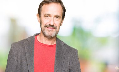 Orta yaş yakışıklı iş adamı yüzünde ciddi bir ifade ile. Basit ve doğal kameraya bakıyor.