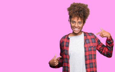 Güzel genç Afro-Amerikan kadın yüzünde gülümseme ile kendinden emin görünüyorsun, kendini gururlu ve mutlu parmakları ile işaret izole arka plan üzerinde gözlük.