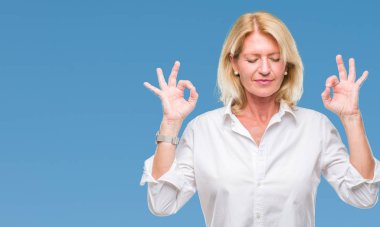 Orta yaş sarışın iş kadını izole arka plan üzerinde dinlenmek ve gülümseyen gözlerle parmak ile meditasyon jest yapıyor kapalı. Yoga kavramı.