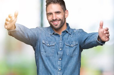 Yakışıklı delikanlı sarılmak için kollarını açarak gülümseyerek kameraya bakarak izole arka plan üzerinde. Neşeli ifade kucaklayan mutluluk.