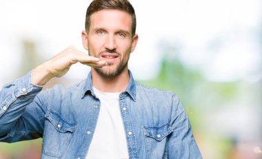 Denim ceket eller eller büyük gösterilen ve büyük boy işareti, ölçü birimi sembolü ile giyen sakal ve mavi gözlü yakışıklı adam. Kameraya bakarak gülümsüyordu. Ölçüm kavramı.