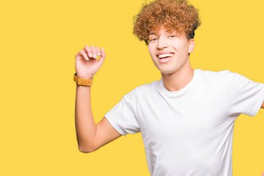 Rahat ve kendinden emin müzik hareket gülümseyerek dans mutlu ve neşeli, casual beyaz t-shirt giyen afro saçlı Genç yakışıklı adam