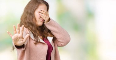 Artı boyutu genç kadın güzel kış ceket elleriyle gözlerini kapsayan izole arka plan üzerinde giyip dur jest ile acı ve korku ifadesi. Utandım ve negatif kavramı.