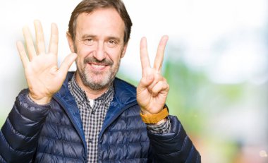 Kış ceket gösterme ve parmakları ile işaret giyen orta yaş yakışıklı adam kendinden emin ve mutlu gülümseyerek süre yedi numara.