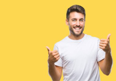 Yakışıklı delikanlı izole arka plan başarı işareti el ile pozitif jest yapıyor üzerinde başparmak gülümseyen ve mutlu. Neşeli bir ifadeyle, kazanan jest kameraya bakıyor.