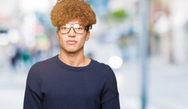 Afro yüzünde ciddi bir ifade ile gözlük takan genç yakışıklı adam. Basit ve doğal kameraya bakıyor.