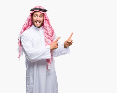 Keffiyeh gülümseyen ve iki elleri ve parmakları ile tarafına işaret kamera bakarak izole arka plan üzerinde giyen genç yakışıklı adam.