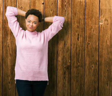 Güzel genç Afro-Amerikan kadın izole arka plan üzerinde rahatlatıcı ve kollar ve eller baş ve boyun, mutlu gülümseyerek arkasında ile germe