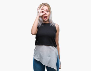 Sürpriz yüz, göz parmaklarının arasından seyir ile ok jest yapıyor izole arka plan üzerinde sarışın genç kadın şok. İmansız ifade.