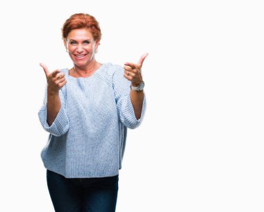 Fotoğraf makinesi ile mutlu ve komik yüz için parmakları işaret izole arka plan üzerinde kış kazak giyen Atrractive üst düzey beyaz Kızıl saçlı kadın. İyi enerji ve vibes.