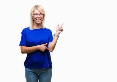 Kameraya bakarak yan el ve parmak ile işaret yüzünde kocaman bir gülümseme ile izole arka plan üzerinde gözlük takan genç güzel sarışın kadın.