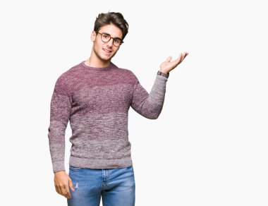 Neşeli sunulması ve kameraya bakarak avucunun ile işaret gülümseyen izole arka plan üzerinde gözlük takan genç yakışıklı adam.