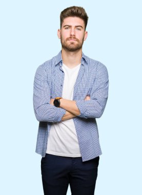 Yüz çapraz silah ile rahat gömlek şüpheci ve sinir, onaylamayan ifade giyen genç yakışıklı sarışın adam. Negatif kişi.