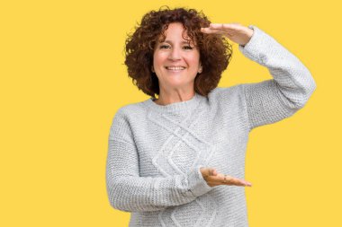 Üzerinde kış kazak giyen güzel orta ager üst düzey kadın arka plan ile büyük ve büyük boy işaret, ölçü birimi sembol gösteren el eller izole. Kameraya bakarak gülümsüyordu. Ölçüm kavramı.