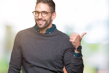 Seyir ve başparmak yanında yukarıyı mutlu yüz ile gülümseyen izole arka plan üzerinde gözlük takan genç yakışıklı adam.