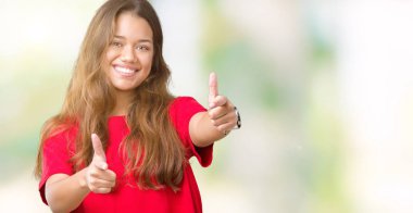 Fotoğraf makinesi ile mutlu ve komik yüz için parmakları işaret izole arka plan üzerinde kırmızı t-shirt giyen genç güzel esmer kadın. İyi enerji ve vibes.