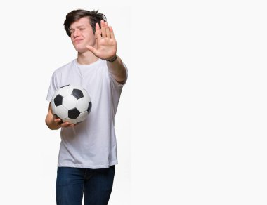 Genç adam açık eliyle dur işareti ile ciddi ve kendine güvenen ifade, savunma jest yapıyor izole arka plan üzerinde futbol futbol topu tutan