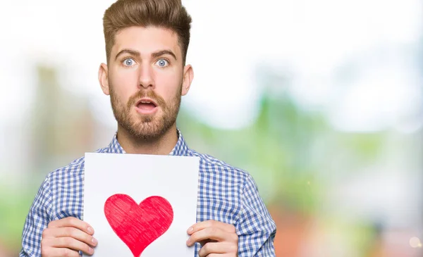 Joven Hombre Guapo Sosteniendo Papel Con Corazón Rojo Asustado Shock —  Fotos de Stock