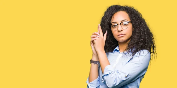 Young beautiful business girl with curly hair wearing glasses Holding symbolic gun with hand gesture, playing killing shooting weapons, angry face