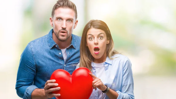 Pareja Joven Enamorada Sosteniendo Corazón Rojo Sobre Fondo Aislado Asustada — Foto de Stock