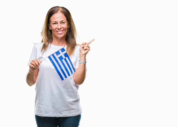 中年のヒスパニック系女性側の手と指で指す非常に幸せの孤立した背景にギリシャの旗を保持しています — ストック写真