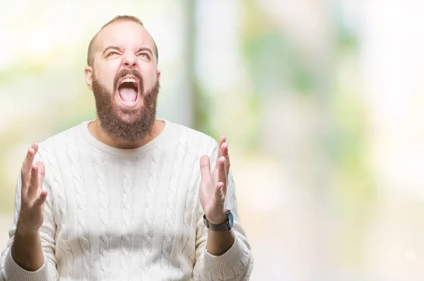 年轻的高加索嬉皮士男子穿着冬季毛衣在孤立的背景疯狂和疯狂的喊声和积极的表情和手臂抬起来的大喊大叫 挫折的概念 — 图库照片