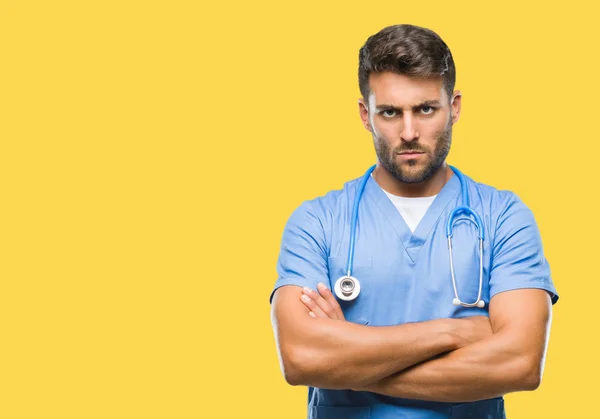 Young handsome doctor nurse man over isolated background skeptic and nervous, disapproving expression on face with crossed arms. Negative person.