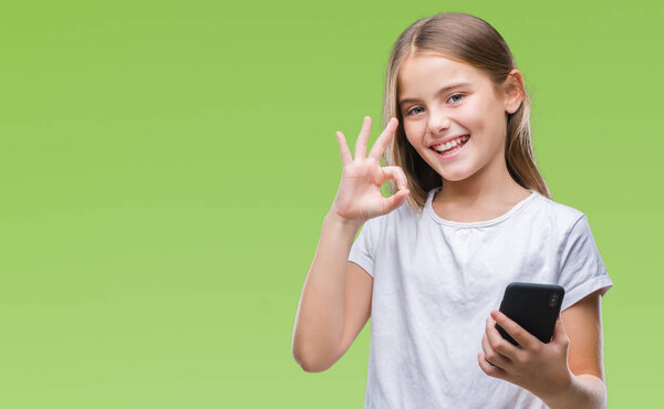 Young beautiful girl sending message texting using smarpthone over isolated background doing ok sign with fingers, excellent symbol