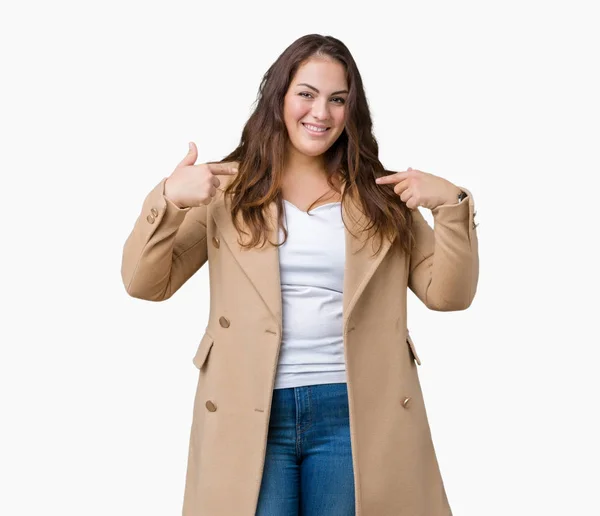 プラスサイズの若い女性は美しい冬のコートを着ている上分離された背景の顔に笑顔と自信を持って 誇りと幸せな指で自分を指しています — ストック写真