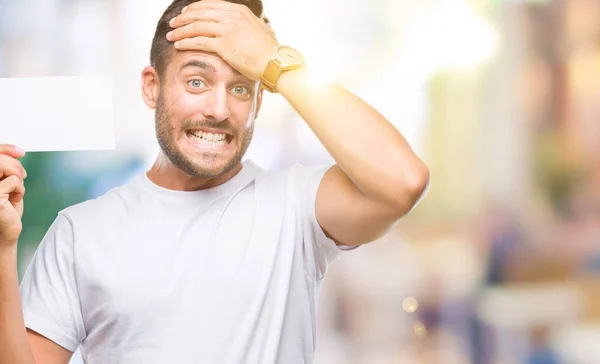 Homem Bonito Jovem Segurando Cartão Branco Sobre Fundo Isolado Estressado — Fotografia de Stock