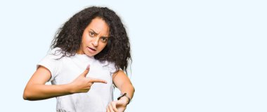 Kıvırcık saçlı acele işaretleme izlemek için zaman, sabırsızlık, üzgün ve kızgın son tarih gecikme için rahat beyaz t-shirt giyen genç güzel kız