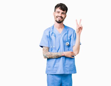 Genç yakışıklı mutlu yüz zafer işareti yaparken kameraya göz kırpıyor ile gülümseyen izole arka plan üzerinde cerrah üniforma giyen adam hemşire. İki numaralı.