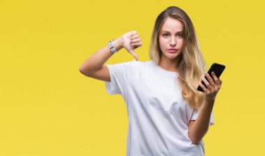 Kızgın yüz, eksi işareti aşağı antipati başparmak ile gösterilen, ret kavramı ile izole arka plan üzerinde akıllı telefon kullanan genç güzel sarışın kadın