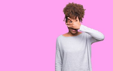 Yüz ve gözler el ile kapsayan şok bakmak izole arka plan üzerinde güzel genç Afro-Amerikan kadın mahcup ifadeyle parmaklarımın arasından arıyorsunuz.