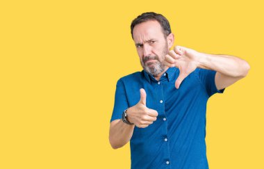 Yakışıklı orta yaş izole arka plan yapmaya başparmak yukarı ve aşağı, anlaşmazlık ve anlaşma ifade üzerinde zarif komuta sizde. Deli çatışma