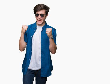 Yakışıklı delikanlı izole arka plan kutlama üzerinde güneş gözlüğü takıyor şaşırttı ve başarı için kaldırdı kollarını açarak hayret ve gözleri açık. Kazanan kavramı.