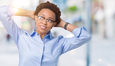 Genç güzel Afro-Amerikan iş kadını izole arka plan üzerinde rahatlatıcı ve kollar ve eller baş ve boyun, mutlu gülümseyerek arkasında ile germe