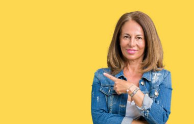 Casual denim ceket izole üzerinde giyen güzel orta yaş kadın yan gösteren reklam, ciddi ve sakin yüz el parmak ile işaret arka plan