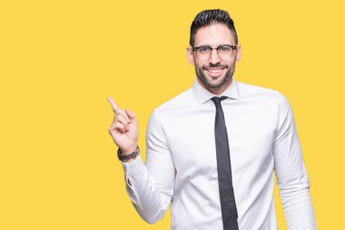 Yüzünde kocaman bir gülümseme ile izole arka plan üzerinde gözlük takan genç yakışıklı iş adamı kameraya bakarak yan el ve parmak ile işaret.